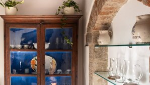 A wooden cabinet with glass doors, a brick wall, and a shelf with clear glass pitchers. - Charming, Romantic Apartment,  50mt from Ponte Vecchio, AC, WIFI, LIFT (Florence)