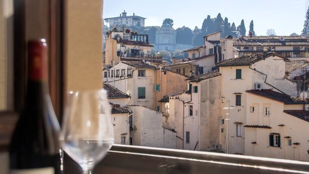 A view of a cityscape through a window with a bottle of wine and a glass. - Charming, Romantic Apartment,  50mt from Ponte Vecchio, AC, WIFI, LIFT (Florence)
