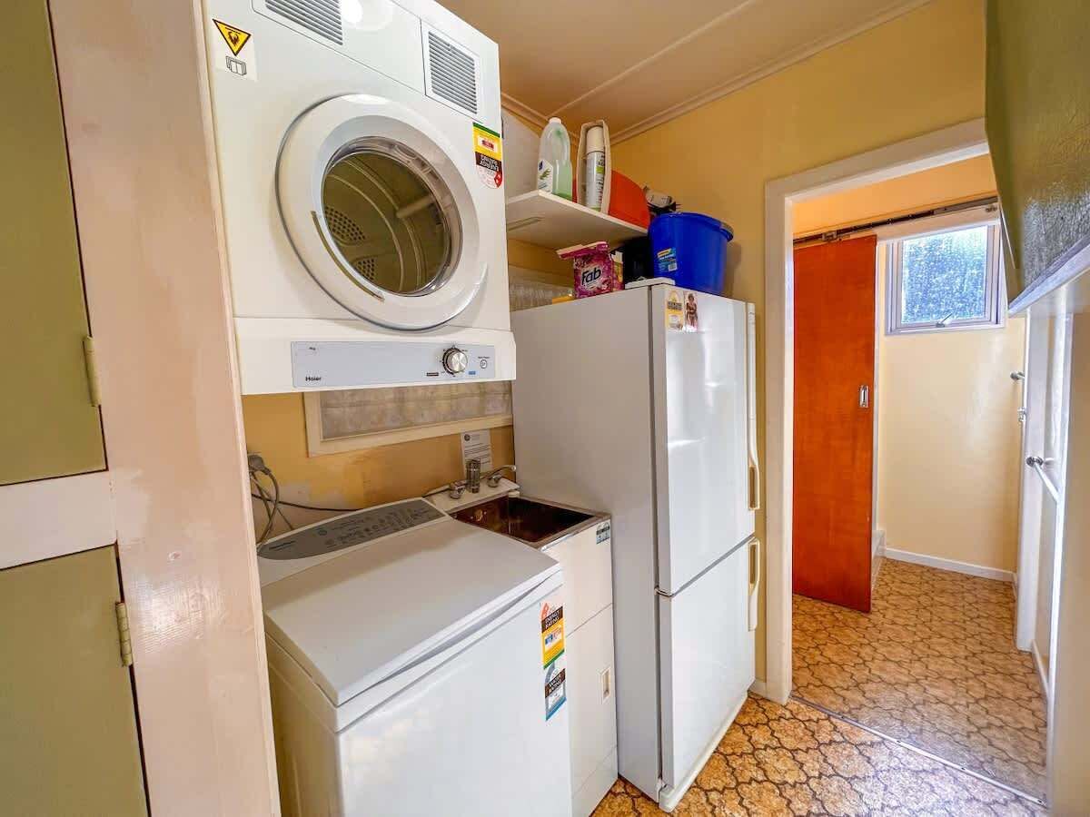 Une cuisine compacte équipée d’un lave-linge, d’un réfrigérateur et d’un évier.