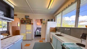 Una cocina compacta con microondas, refrigerador y lavamanos.