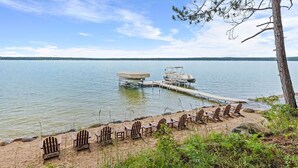 A lakeside setting with a dock, chairs, and a boat.