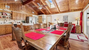 Comedor de madera con una mesa larga, sillas y un ventilador de techo.