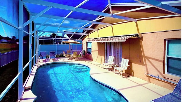 Uma piscina com espreguiçadeiras e um terraço coberto.
