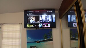 A television mounted on a wall displaying a Roku Channel interface with various shows and movies.