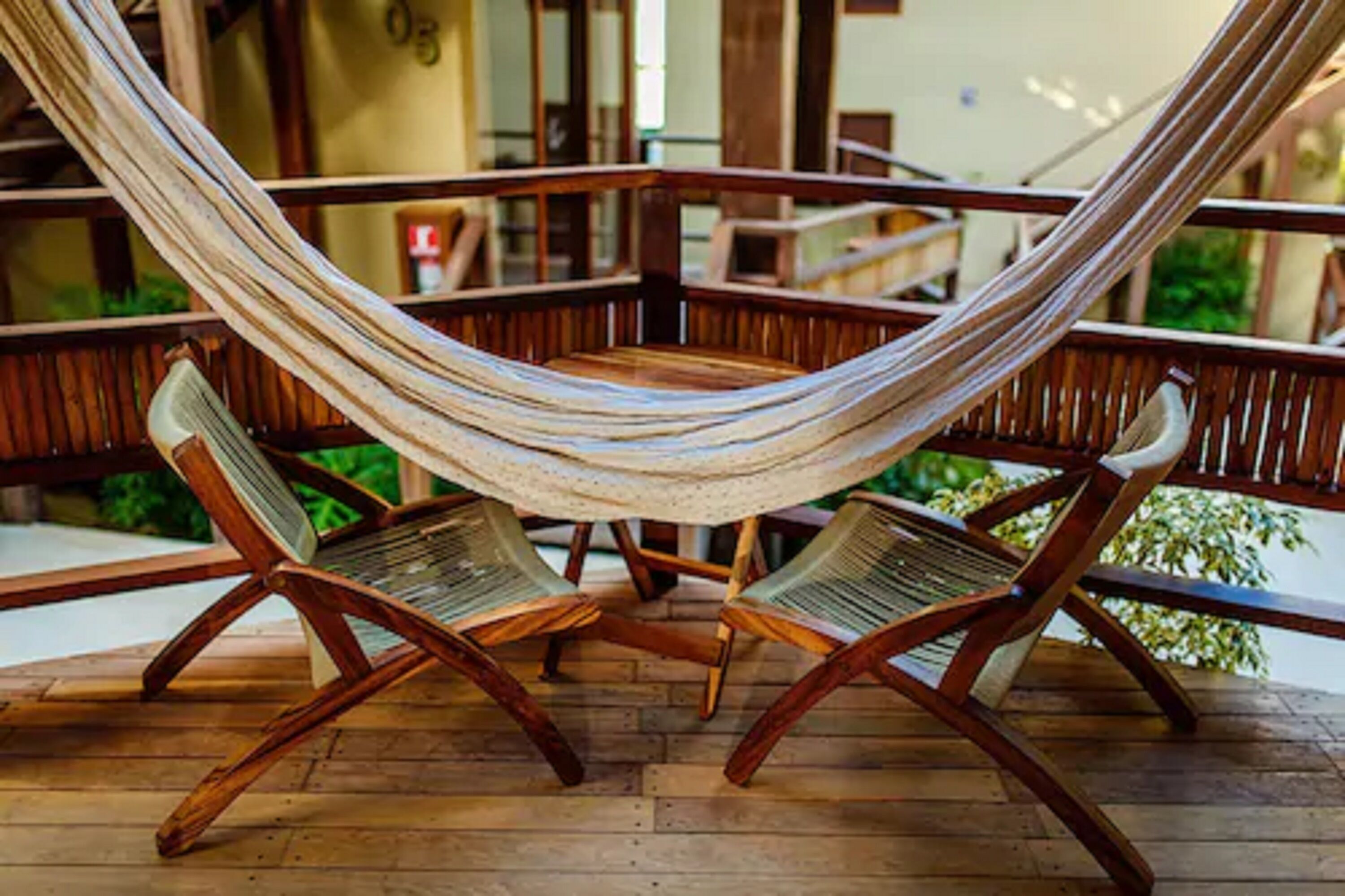 Un sillón hamaca sobre una terraza de madera, con vista a un edificio al fondo.