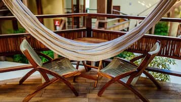Un sillón hamaca sobre una terraza de madera, con vista a un edificio al fondo.