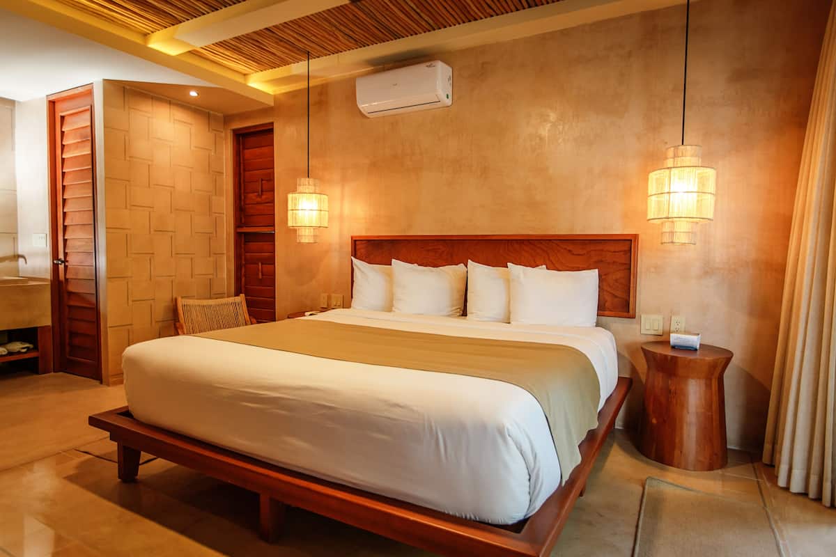 Ein Hotelzimmer mit einem großen Bett, einem Holz-Kopfteil, zwei Nachttischlampen und einem kleinen Holztisch.
