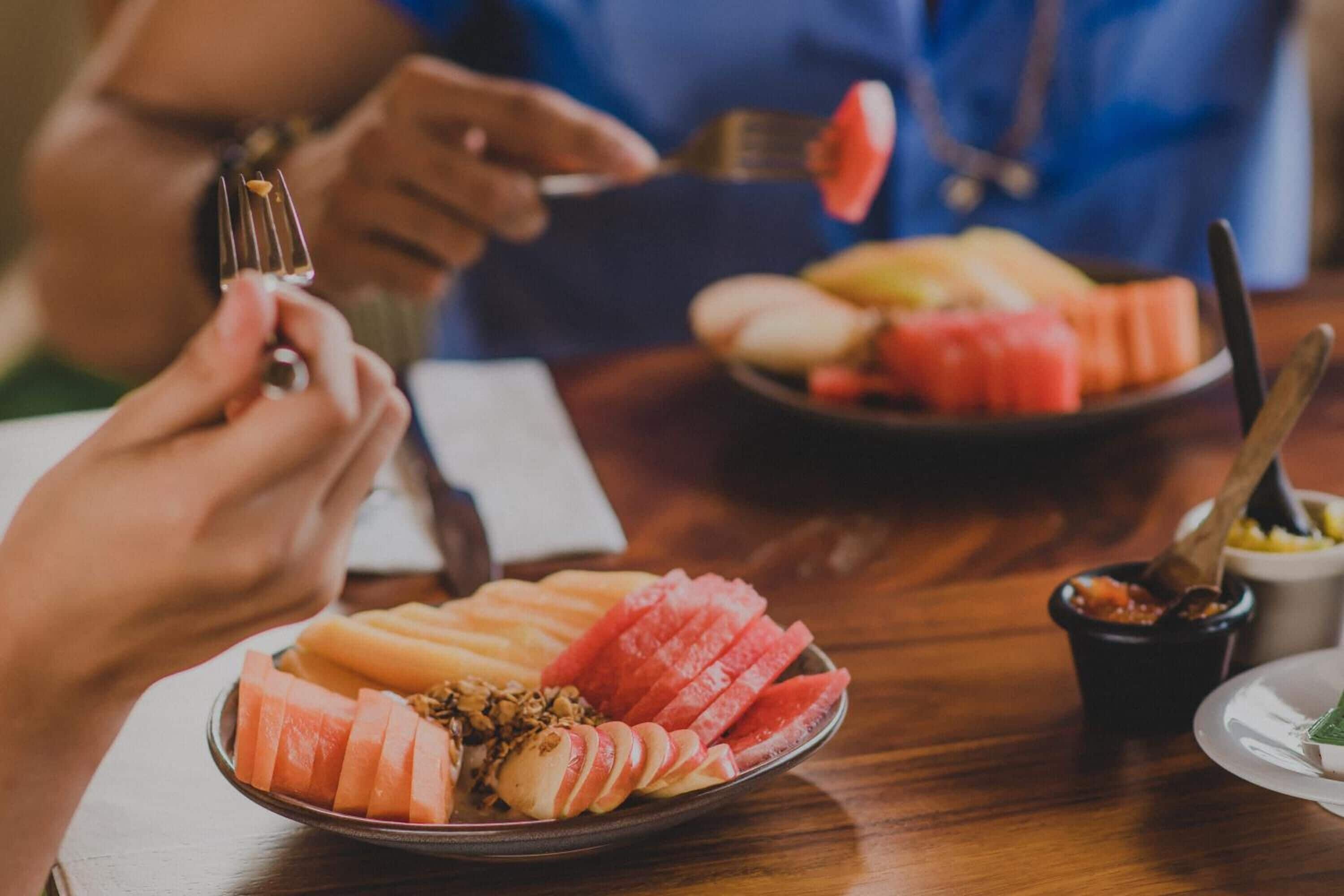 Un tavolo da pranzo con piatti di frutta a fette e una piccola ciotola di salsa.