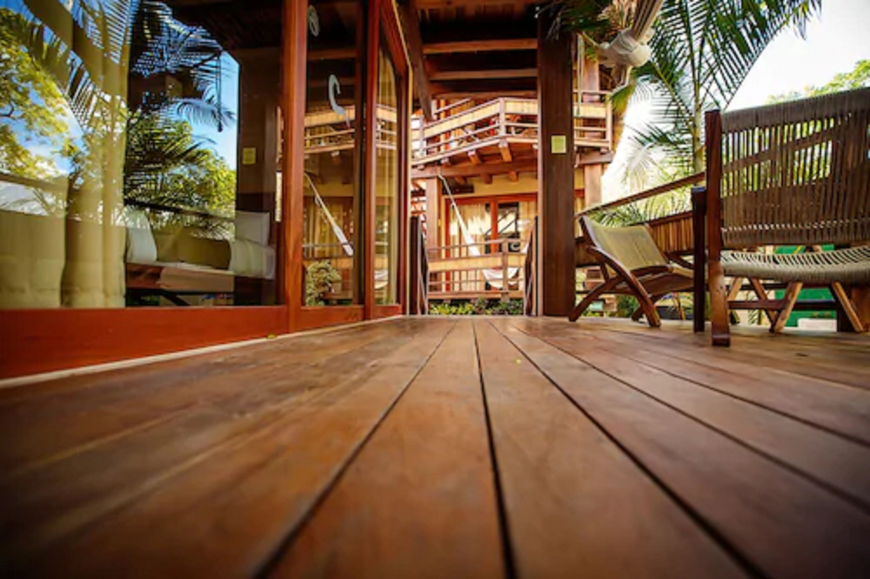 A wooden deck with a view of a wooden structure with balconies and a bench.