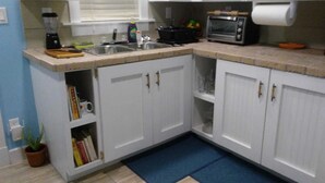 A kitchen with white cabinets, a sink, a toaster, and a blender. - The Colonial Rental Suite, Moss Town Exuma (Moss Town)