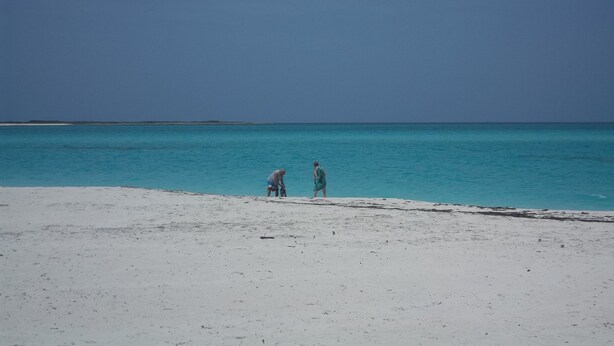 A beach with two people walking along the shore. - The Colonial Rental Suite, Moss Town Exuma (Moss Town)