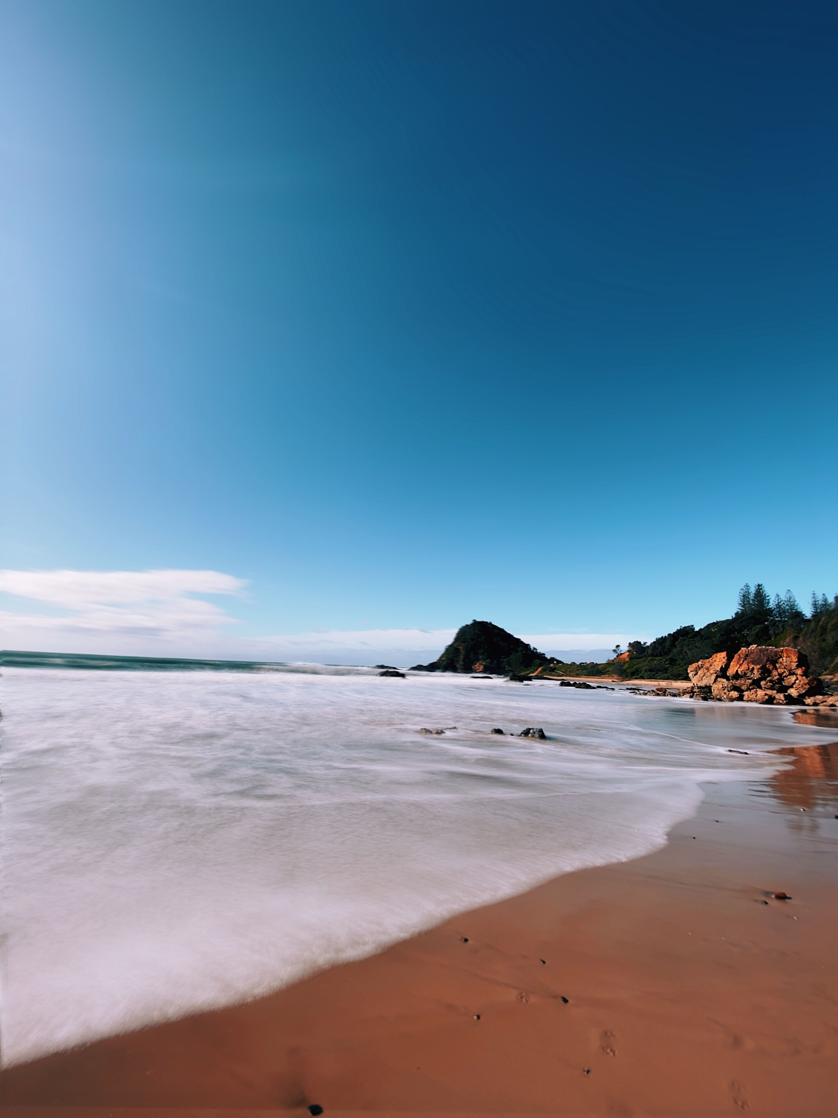 Une plage avec un ciel dégagé et une mer calme.