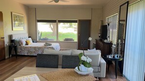 A spacious room with a bed, a sofa, a dining table, and a television. - Fi s Beach House directly opposite beach and park! (Port Macquarie)