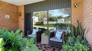A covered patio with wicker furniture and potted plants. - Fi s Beach House directly opposite beach and park! (Port Macquarie)