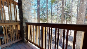 A wooden deck with a stone wall, overlooking a forested area. - Homey Vintage Condo, Balcony, Forested Location. Tennis Courts & Pool On-site (Mammoth Lakes)