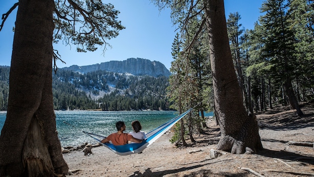 A hammock between two trees overlooking a lake with mountains in the background. - Homey Vintage Condo, Balcony, Forested Location. Tennis Courts & Pool On-site (Mammoth Lakes)