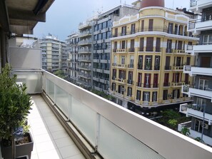 A balcony with a view of multi-story buildings, including a yellow building with red shutters. - Luxury in the heart of the city (Thessaloniki)