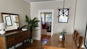 A dining area with a wooden table and chairs, a potted plant, and a chandelier.