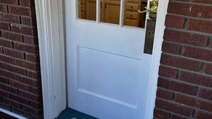 A white door with a glass panel, a brass door handle, and a doormat with the word "hello".