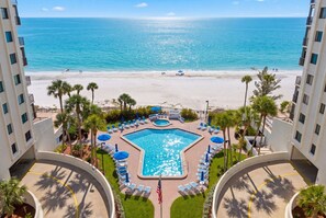 Ein Hotel mit Swimmingpool, Blick auf den Strand und Palmen.