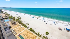 A beach resort with a swimming pool, beach umbrellas, and a clear view of the ocean. - Ocean Sands 1107: Amazing Gulf Front Retreat (Madeira Beach)