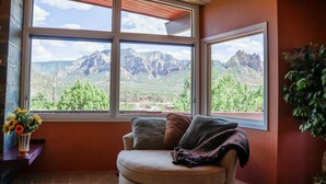 Ein Zimmer mit großem Fenster und Blick auf Berge und Grünflächen.