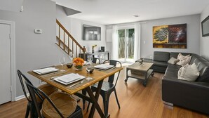 A modern living room with a dining area, a sofa, and a painting on the wall. - BickelScape: Private Yard & Near DC (Sterling)