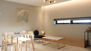 A modern meeting room with a white table, chairs, a bench, and a ceiling light fixture. - Brown dot Hotel Palyong (Changwon)