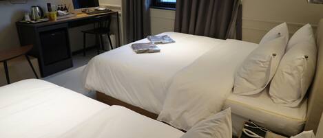 Une chambre d’hôtel avec deux lits, un bureau avec un ordinateur et une télévision.