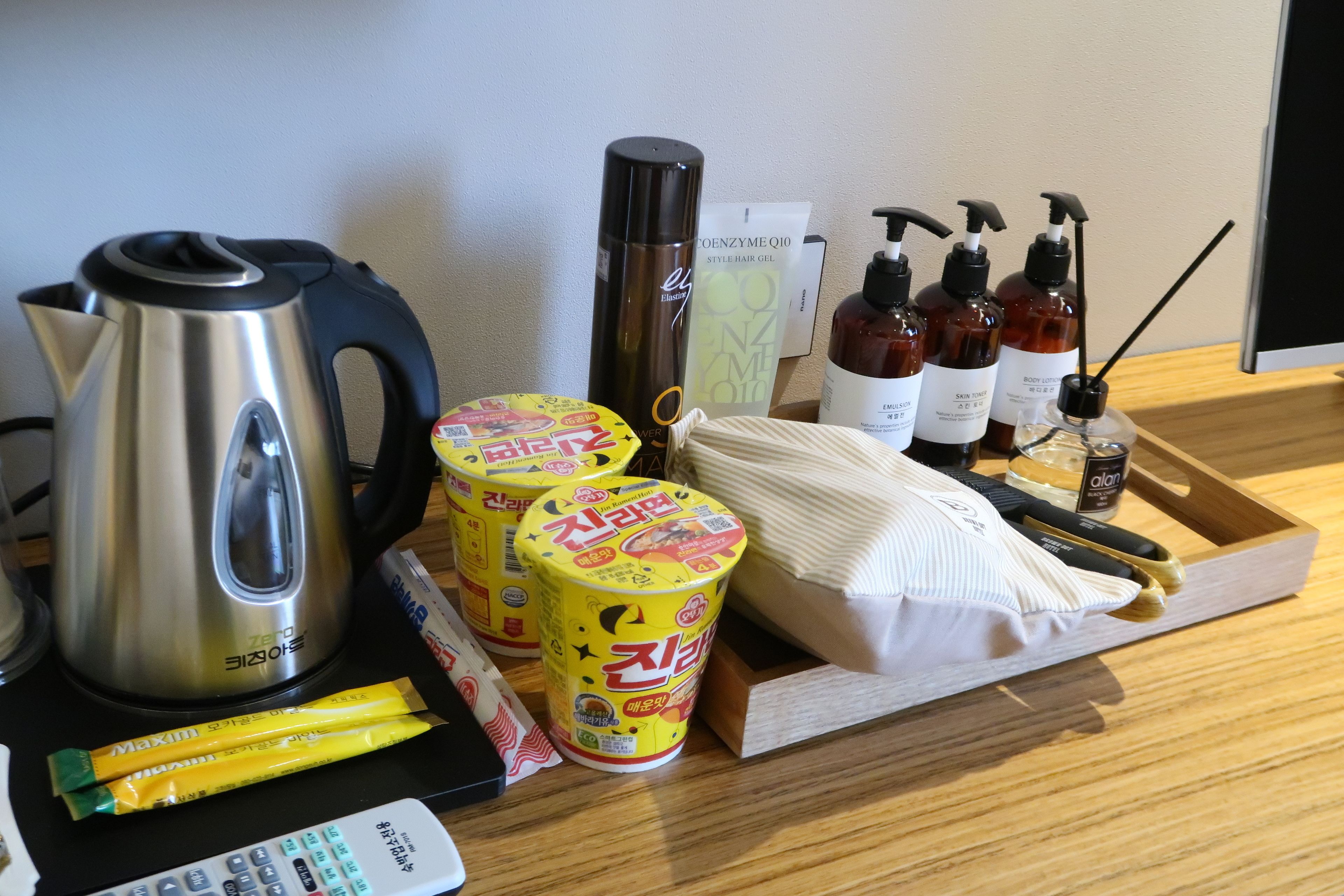 Une table sur laquelle se trouvent une bouilloire, du gel coiffant, des produits de soins pour la peau et des aliments emballés.