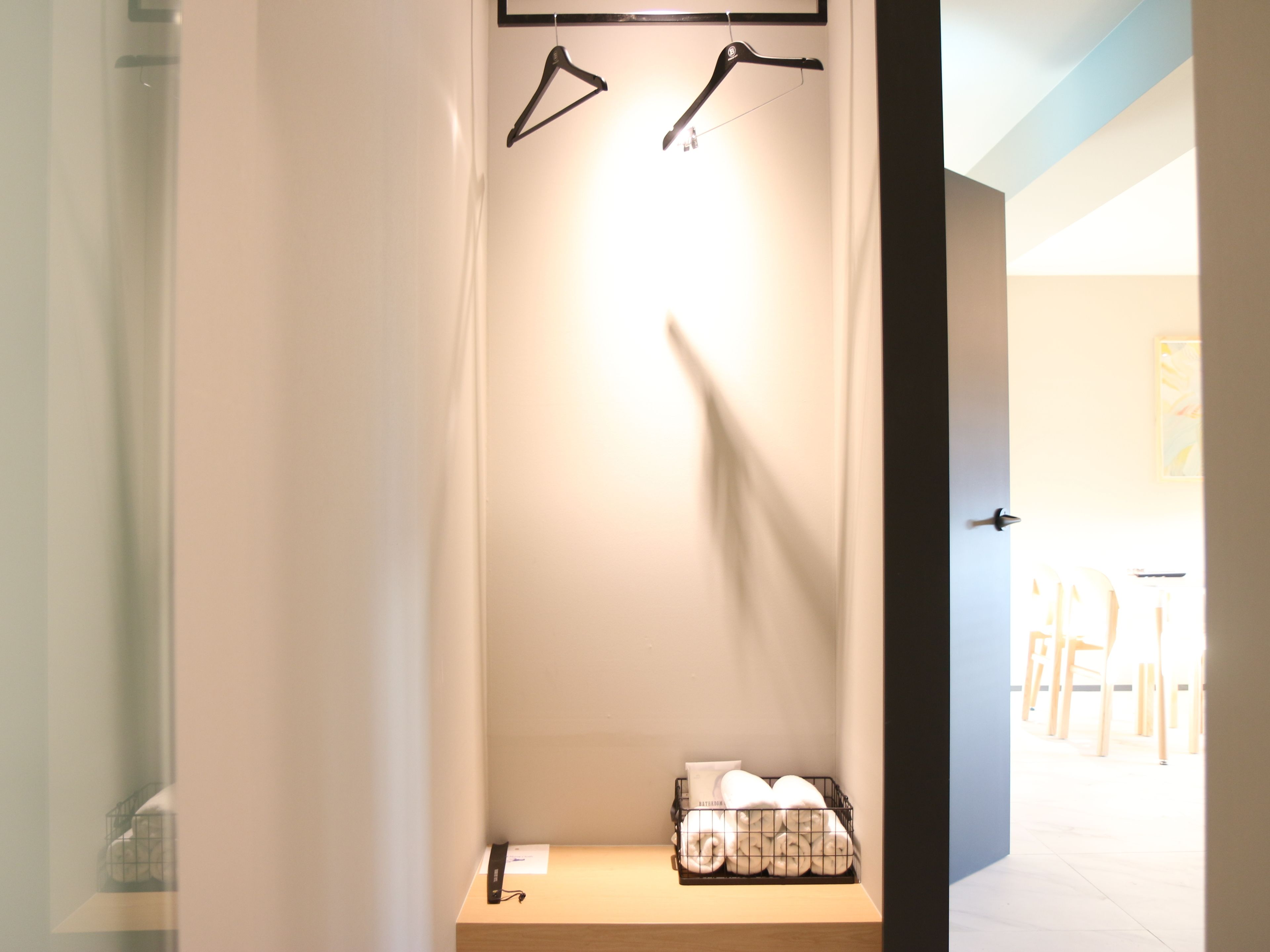 A hotel room with a bed, a small table with towels, and a coat rack with hangers.