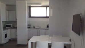 A compact kitchen with a microwave, sink, and cabinets. There is a dining table with chairs and a window above it. - Ground Floor With Stunning Sea Views And Private Terrace, Shared Pool (Pollença)