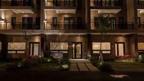 Un hôtel à plusieurs étages au design moderne, doté de balcons, de grandes fenêtres et d’une entrée bien éclairée.