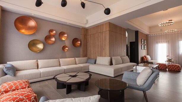 Un salon moderne avec un canapé d’angle, une table basse ronde et un fauteuil bleu.