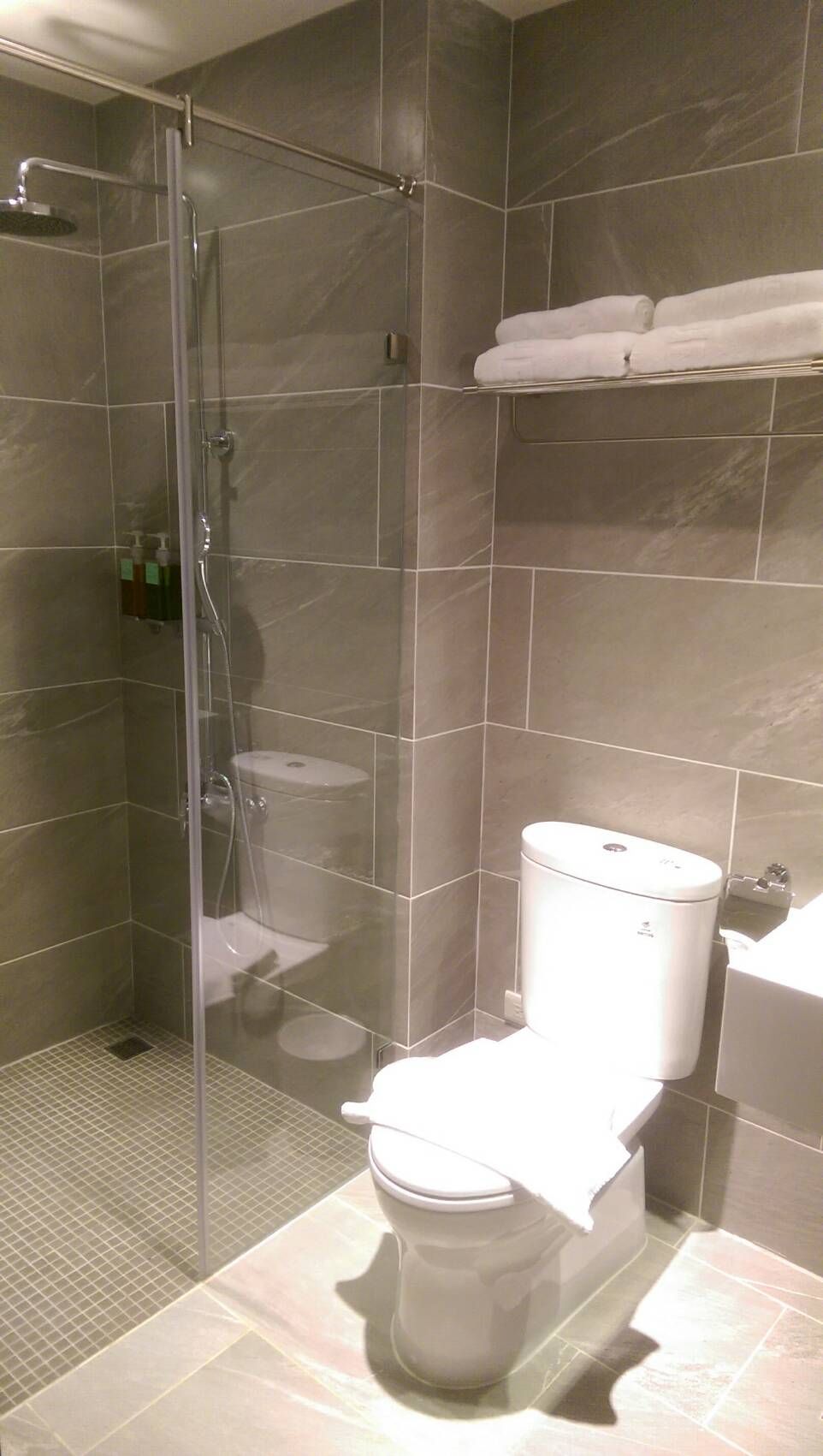 A bathroom with a glass-enclosed shower, a toilet, and a sink.