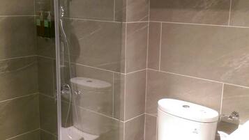 A bathroom with a glass-enclosed shower, a toilet, and a sink.