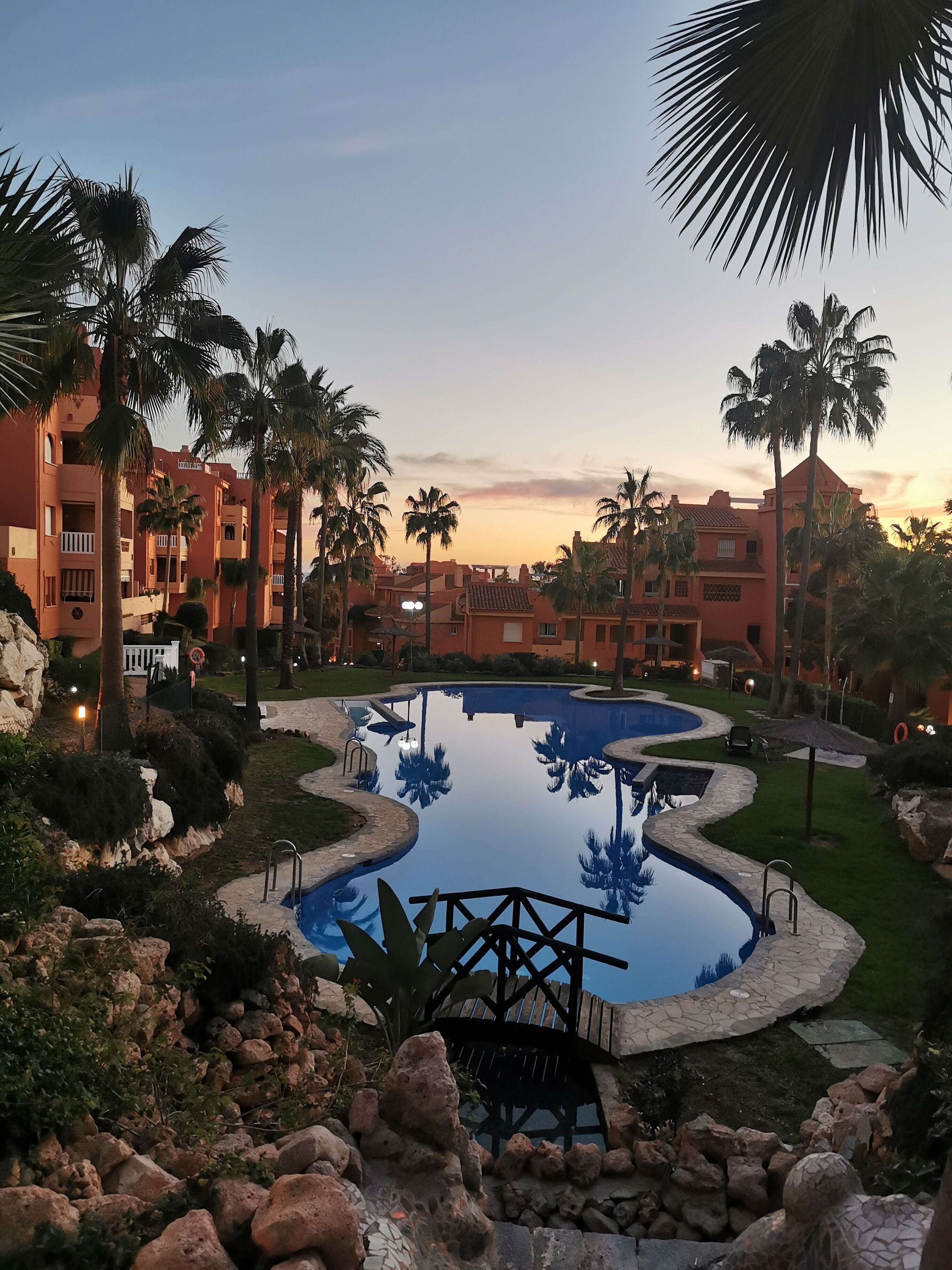 Ein Resort mit Swimmingpool, Palmen und Sonnenuntergang.