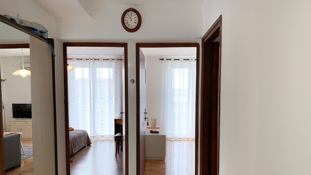 Ein Hotelzimmer mit Bett, Schreibtisch, Stuhl, Fernseher und einer Uhr an der Wand.