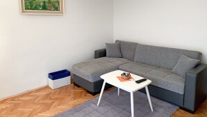 Ein modernes Wohnzimmer mit grauem Sofa, einem weißen Couchtisch und einem Bild an der Wand.