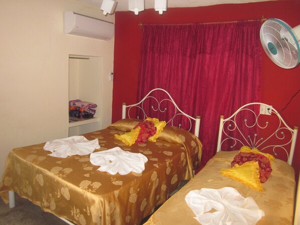Two single beds with matching headboards and footboards, each adorned with a floral-patterned bedspread and decorative pillow.