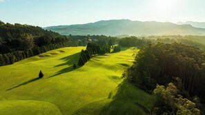 Um campo de golfe com vários fairways, armadilhas de areia e uma área arborizada.