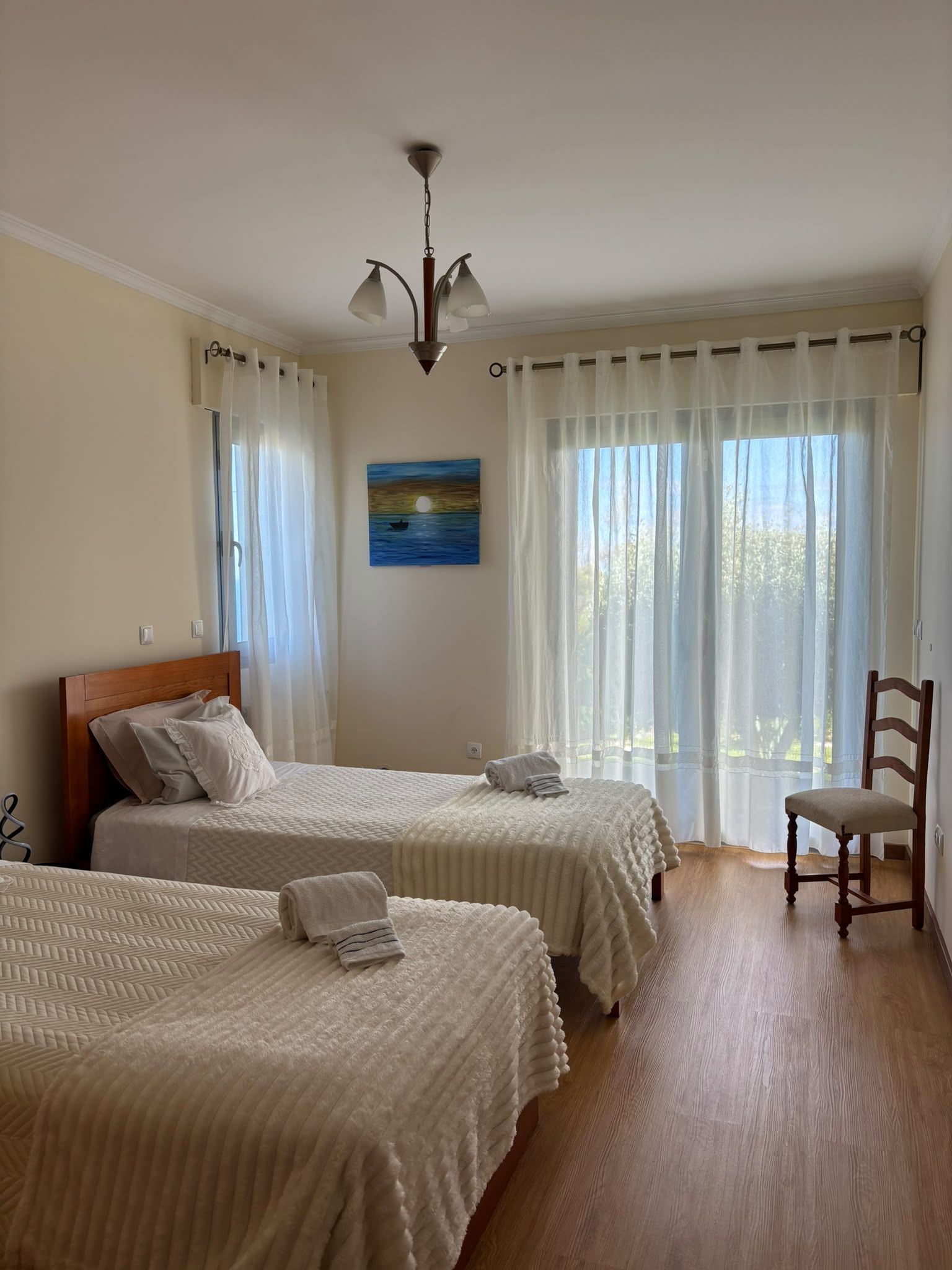 Ett hotellrum med två sängar, en trästol, en tavla och utsikt över omgivningarna.