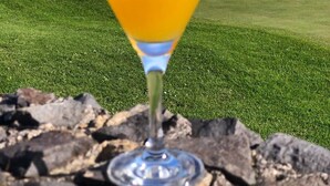 A martini glass with a yellow beverage on a rocky surface, overlooking a golf course with a view of the ocean and hills. - House / Villa - Santa Cruz (Santa Cruz)