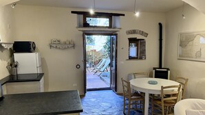 A kitchen with a refrigerator, microwave, and a dining area with a table and chairs. - House with garden in the historical center House with character. (Capoliveri)