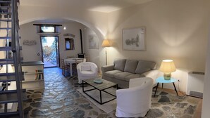 A cozy living room with a stone floor, a sofa, a coffee table, and a lamp. - House with garden in the historical center House with character. (Capoliveri)