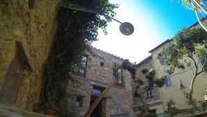 A courtyard with stone walls, a wooden door, and a metal gate. - House with garden in the historical center House with character. (Capoliveri)