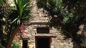 A stone building with a wooden door and a window above it. - House with garden in the historical center House with character. (Capoliveri)