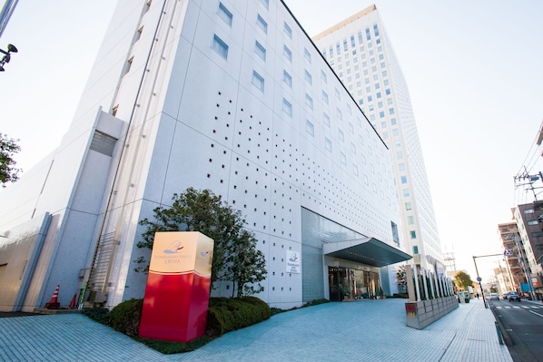 A modern hotel building with a distinctive facade featuring a pattern of small windows and a large, colorful entrance sign.