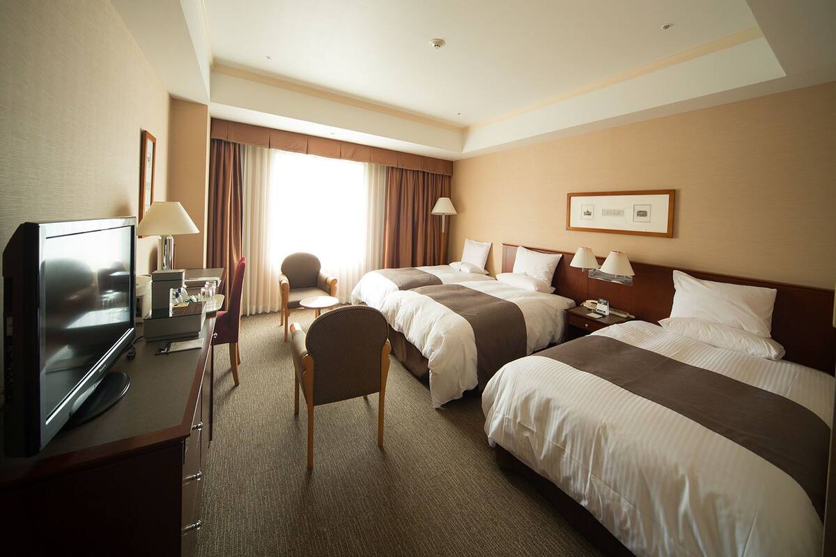 Une chambre d’hôtel avec deux lits, une télévision, un bureau et une chaise.