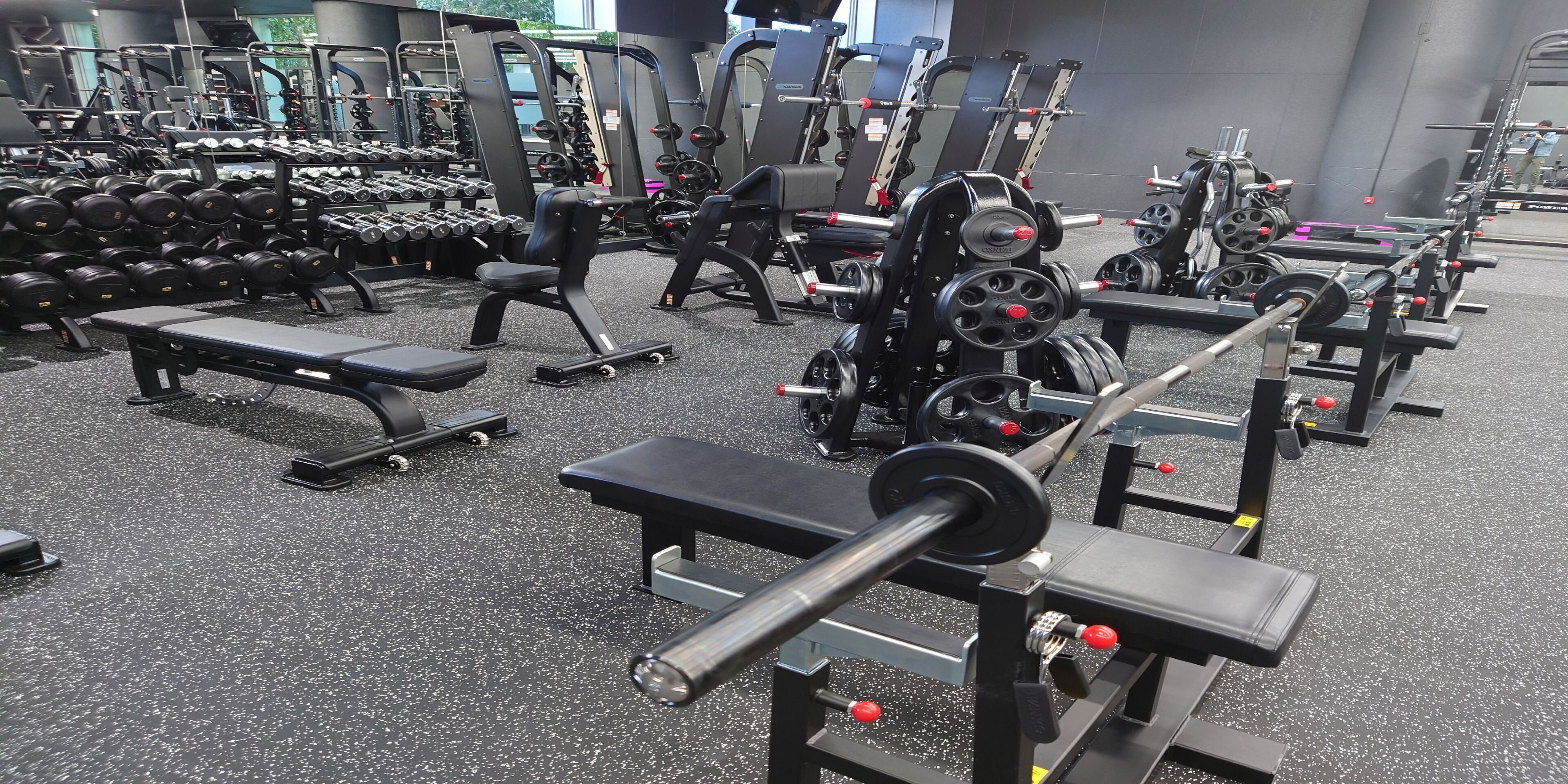 A gym with various weightlifting equipment, benches, and dumbbells.